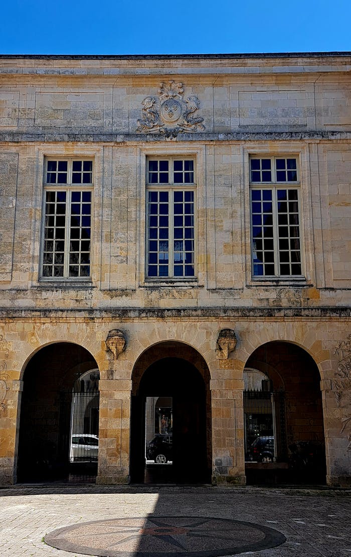 A classic stone building featuring arched entrances and detailed architectural elements under a clear blue sky.